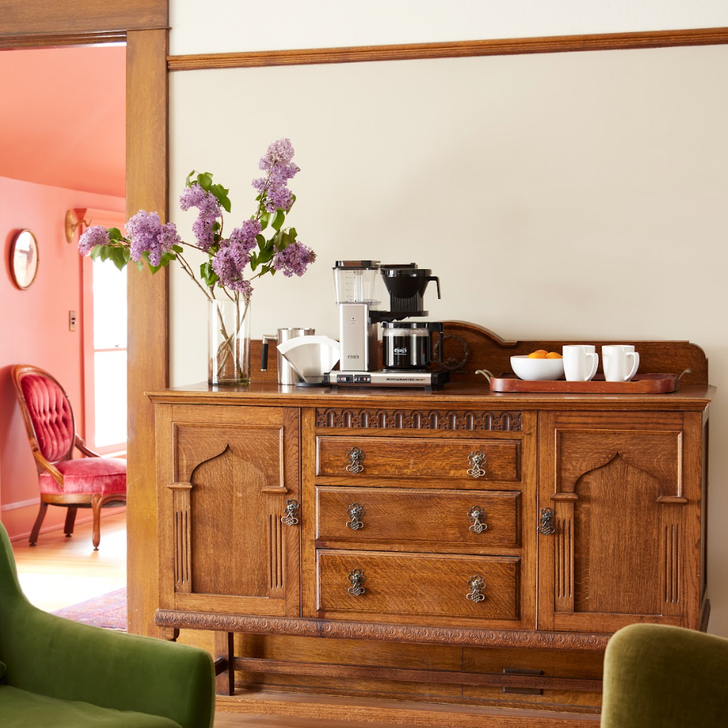 Moccamasters KBG Select Polished Silver Lifestyle Foto op een houten kast met bloemen en kleuren op de achtergrond.