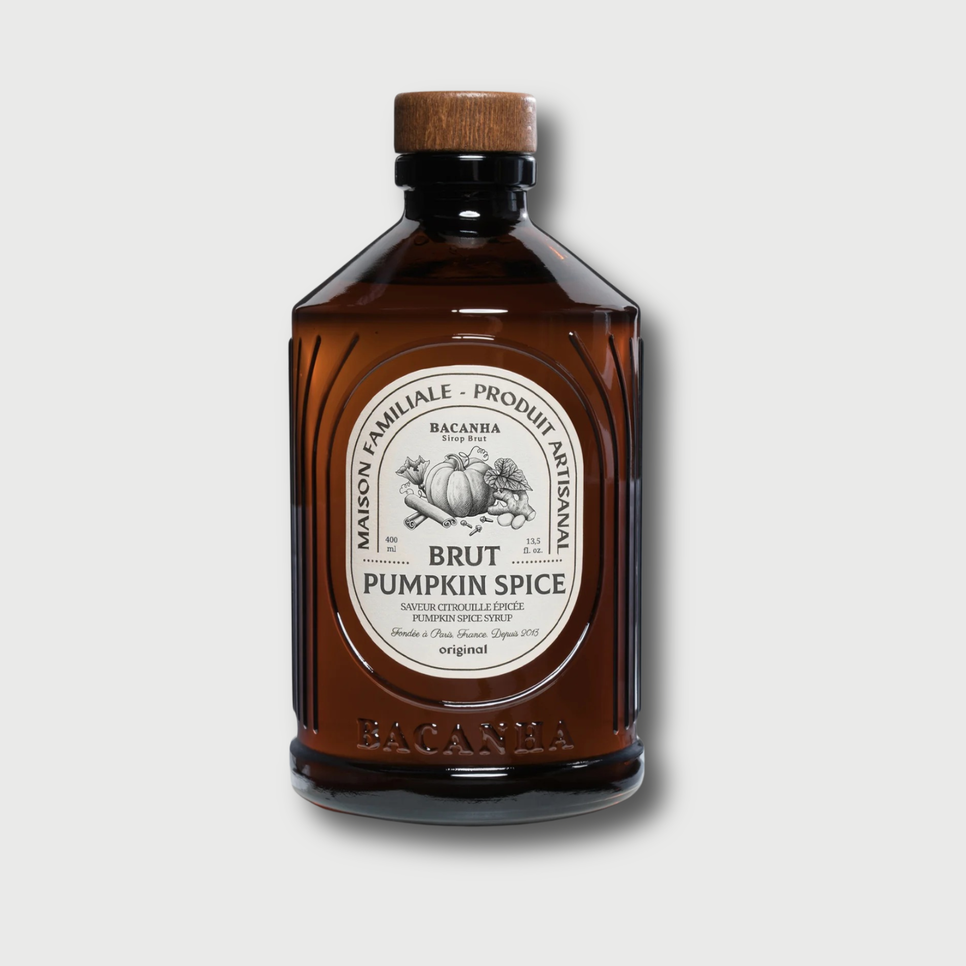 Brown glass Brut Bacanha pumkin spice bottle with wooden cap on a light gray background