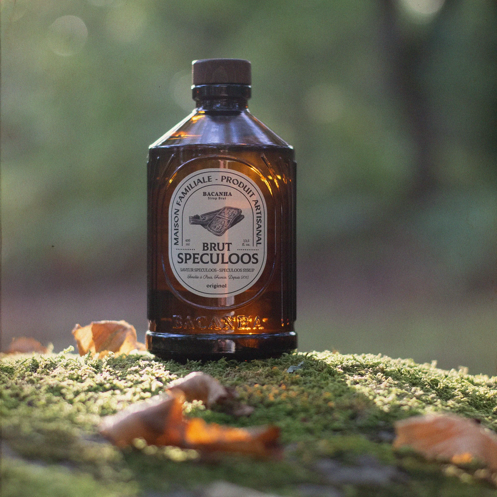 Bottle of bacanha Speculoos sirup on a mossy surface with a blurred natural background