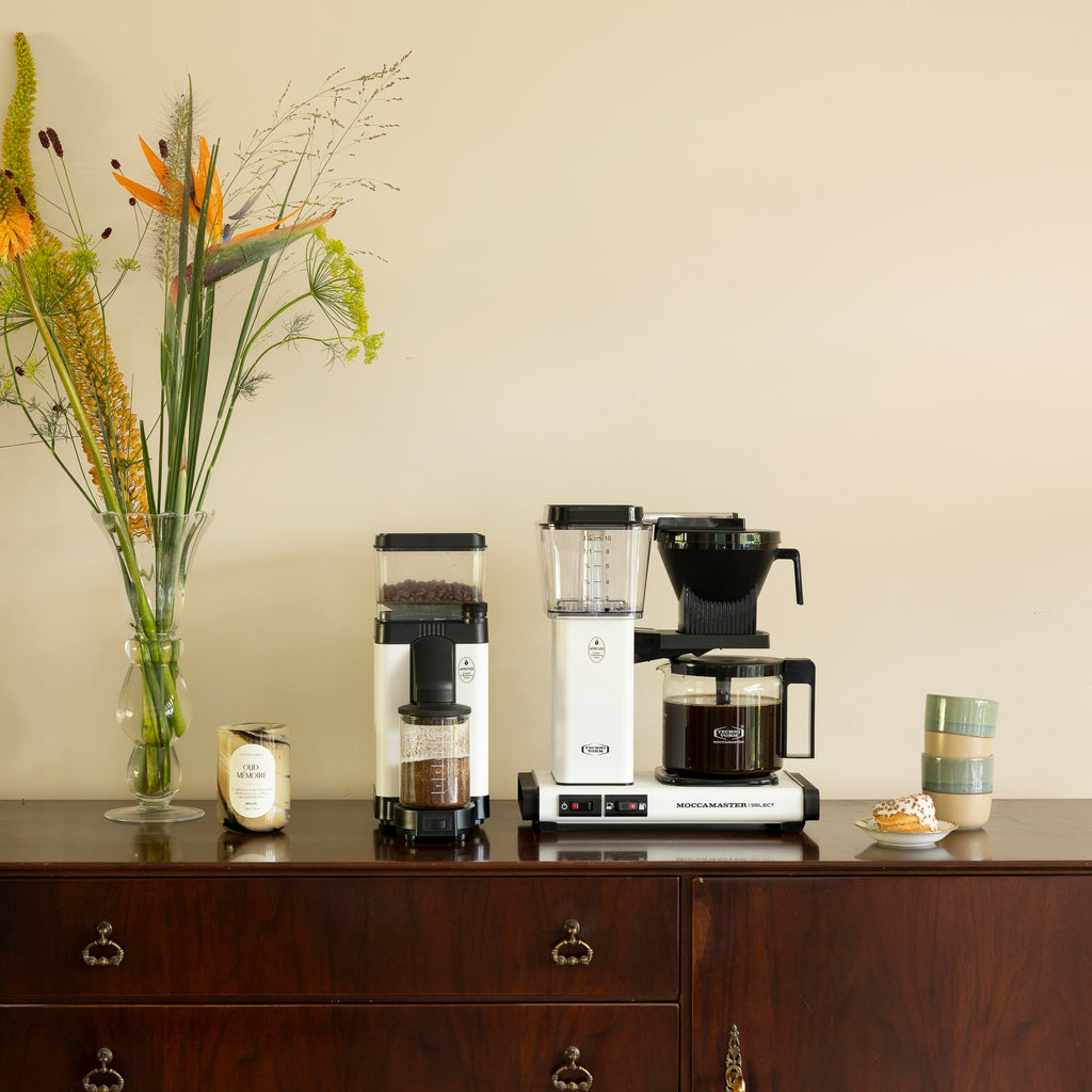 Moccamaster KGB Select Matt White Lifestyle Foto met bloemen en keramieke kopjes op een robuuste kast