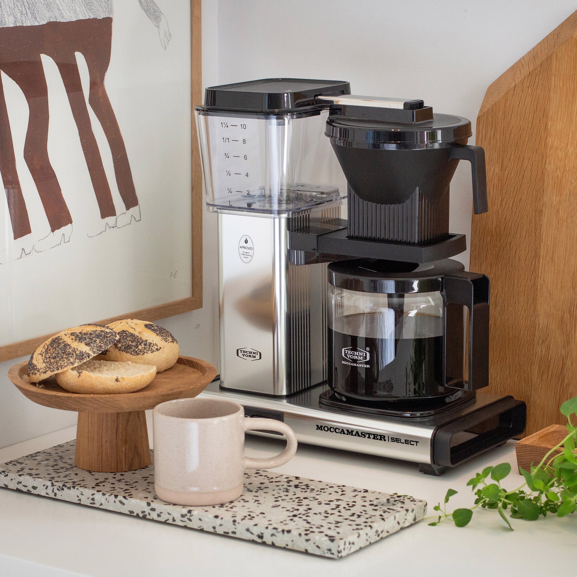 Moccamaster KBG Select Polished Silver Filtermachine lifestyle foto op een lichte achtergrond met houten accenten